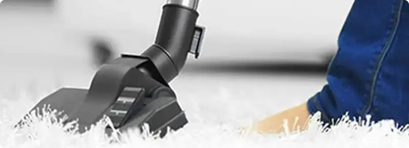 Close-up of a professional vacuuming a white carpet in San Diego.