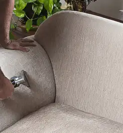 Professional upholstery cleaner deep-cleaning a fabric sofa with a handheld extraction tool and hose Chula Vista, CA.